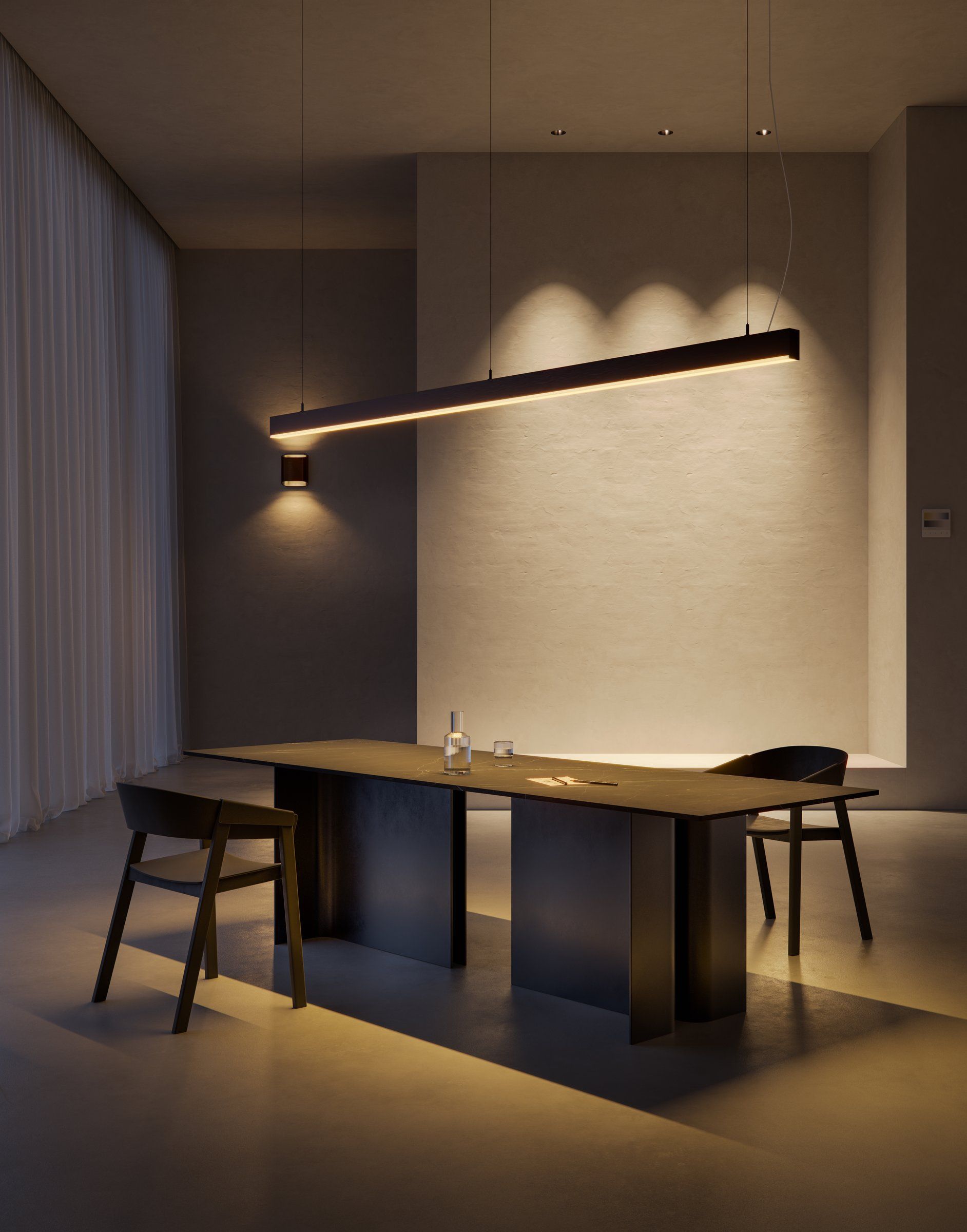 Donkere eettafel onder een lange lijnvormige hanglamp die de tafel en de wand erachter verlicht, met een wandlamp ernaast